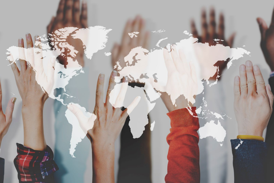 Hands from people of all different races are raised with a world map in the foreground.